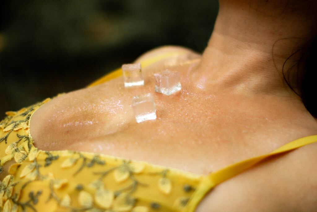 Ice cubes and water droplets are resting on a womans chest as she leans back